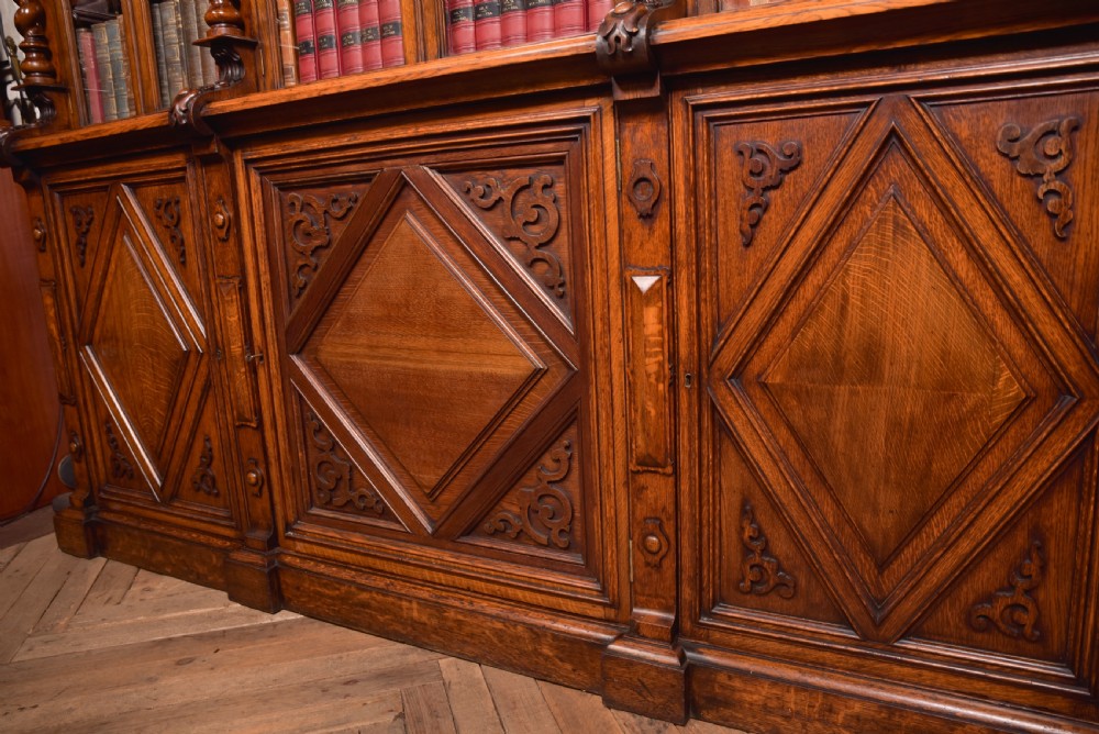 A large Victorian oak bookcase featuring glazed upper doors flanked by barley twist columns with turned finials above carved diamond panel doors. View XXIII