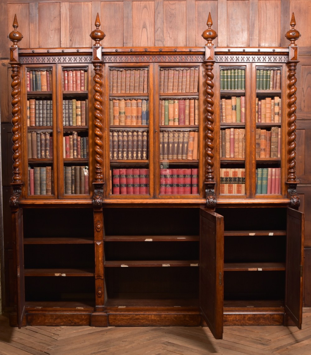 A large Victorian oak bookcase featuring glazed upper doors flanked by barley twist columns with turned finials above carved diamond panel doors. View XXVII