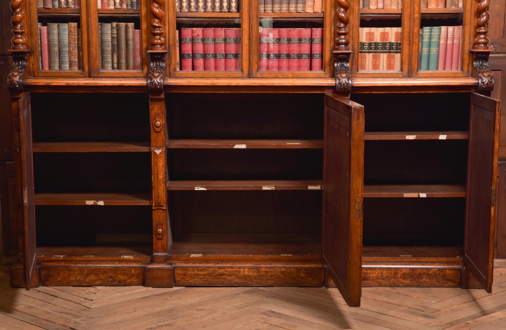 A large Victorian oak bookcase featuring glazed upper doors flanked by barley twist columns with turned finials above carved diamond panel doors. View XXVIII