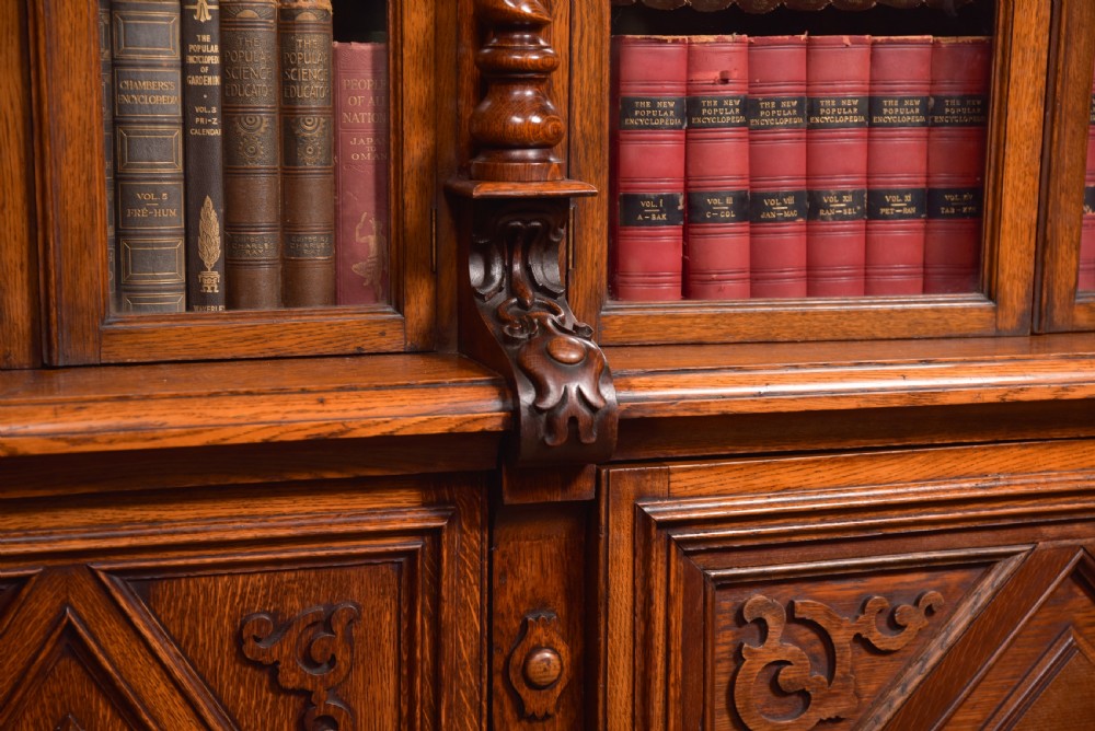 A large Victorian oak bookcase featuring glazed upper doors flanked by barley twist columns with turned finials above carved diamond panel doors. View XXIX