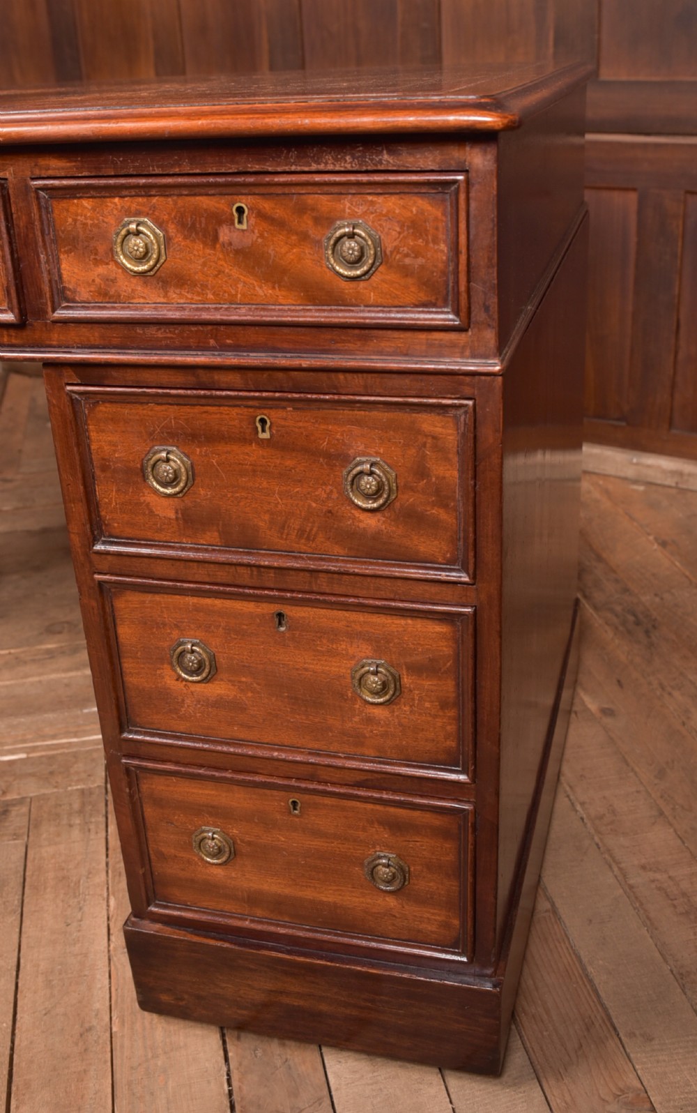 An Edwardian mahogany pedestal desk with nine drawers, brass ring handles, and a leather-inset writing surface. View II