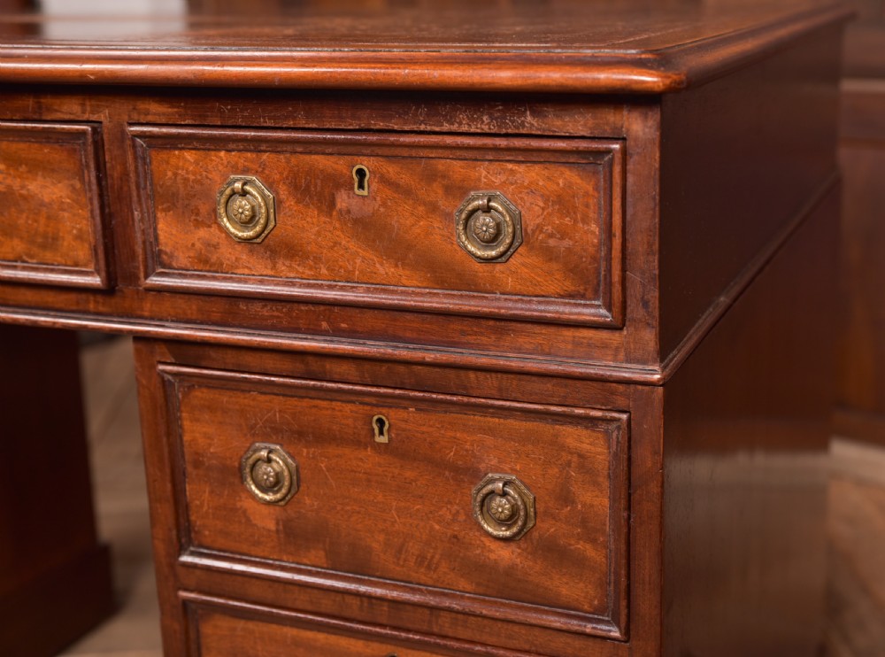 An Edwardian mahogany pedestal desk with nine drawers, brass ring handles, and a leather-inset writing surface. View III