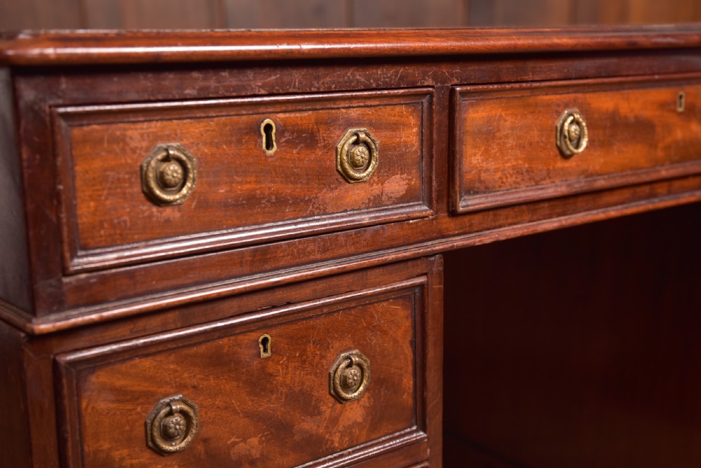 An Edwardian mahogany pedestal desk with nine drawers, brass ring handles, and a leather-inset writing surface. View V