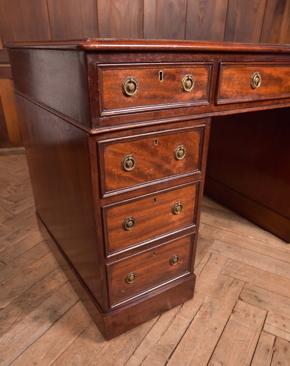 An Edwardian mahogany pedestal desk with nine drawers, brass ring handles, and a leather-inset writing surface. View VI