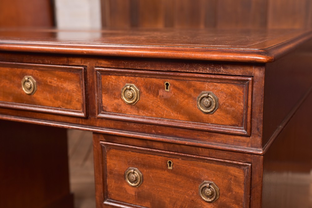 An Edwardian mahogany pedestal desk with nine drawers, brass ring handles, and a leather-inset writing surface. View VII