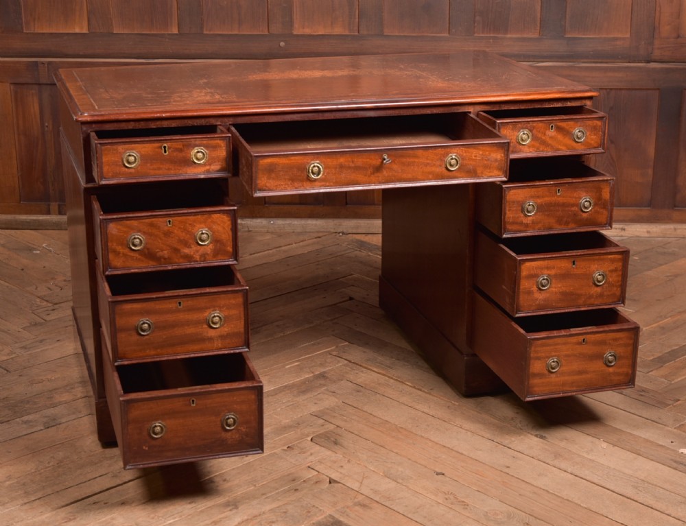 An Edwardian mahogany pedestal desk with nine drawers, brass ring handles, and a leather-inset writing surface. View IX