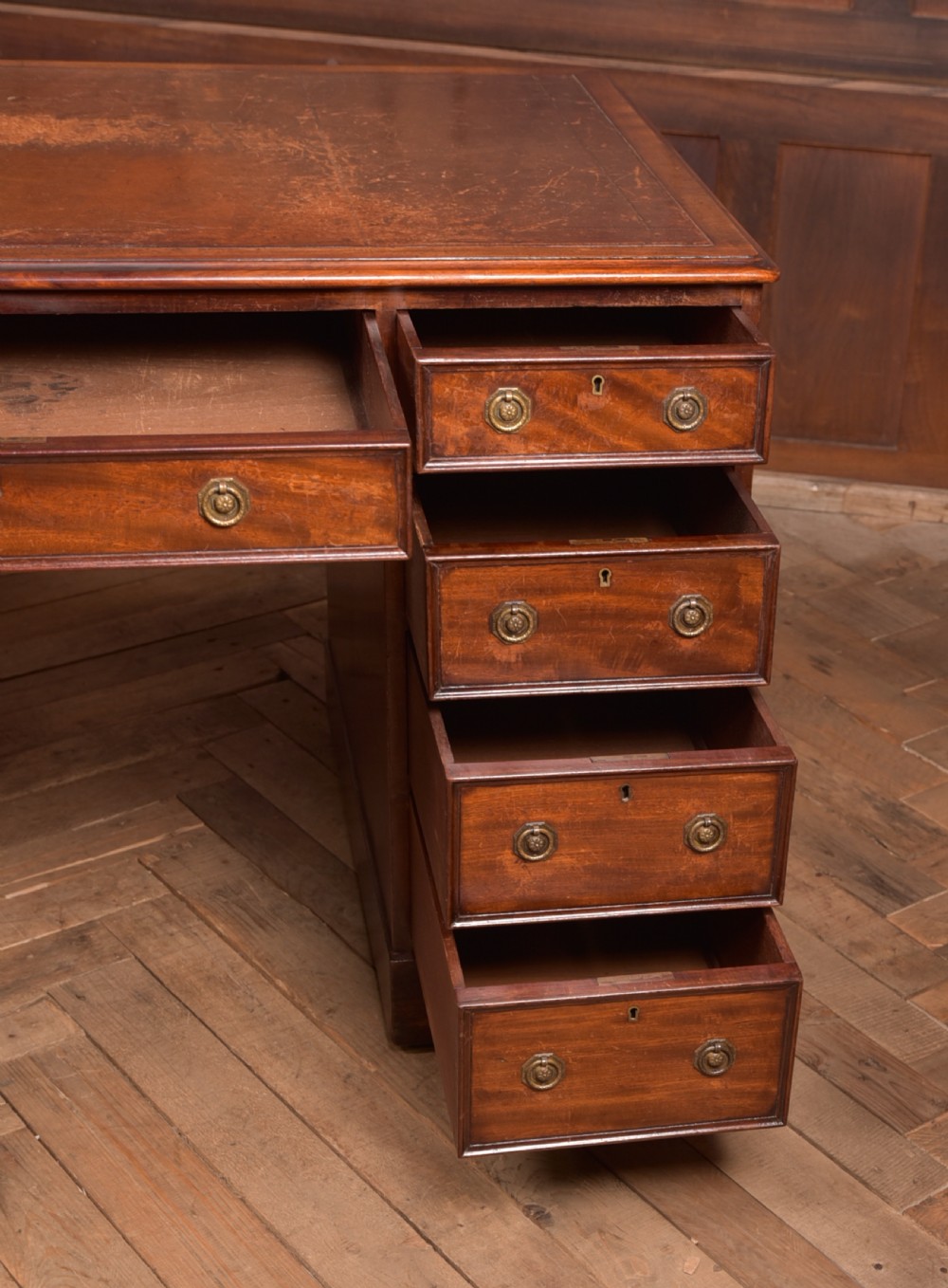 An Edwardian mahogany pedestal desk with nine drawers, brass ring handles, and a leather-inset writing surface. View X