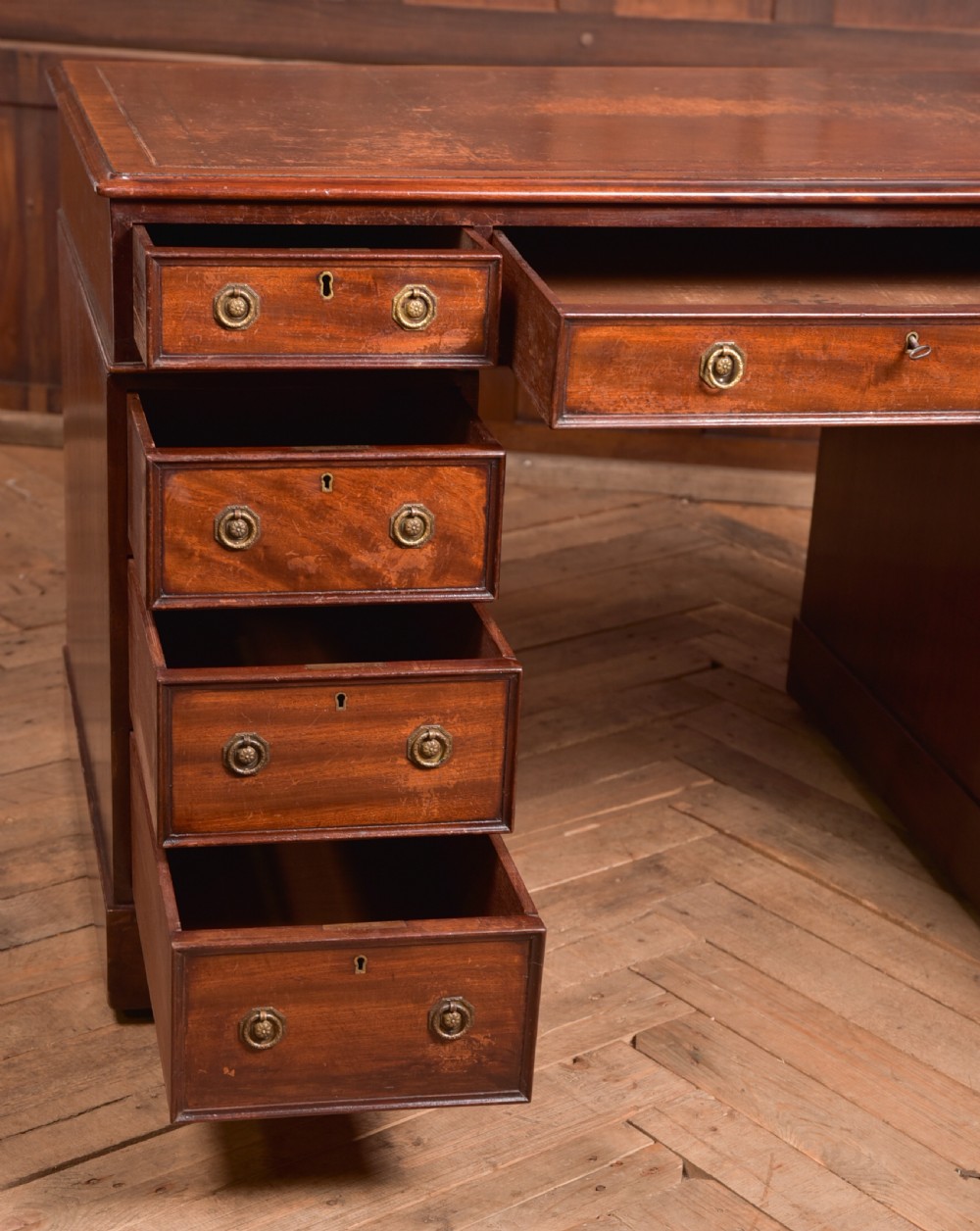An Edwardian mahogany pedestal desk with nine drawers, brass ring handles, and a leather-inset writing surface. View XII