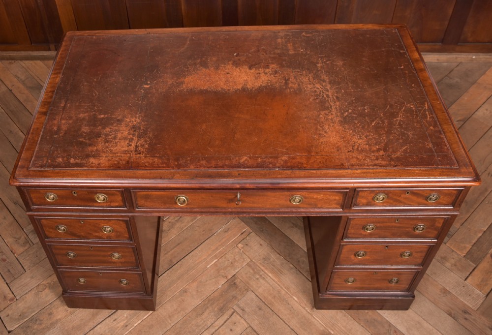 An Edwardian mahogany pedestal desk with nine drawers, brass ring handles, and a leather-inset writing surface. View XV