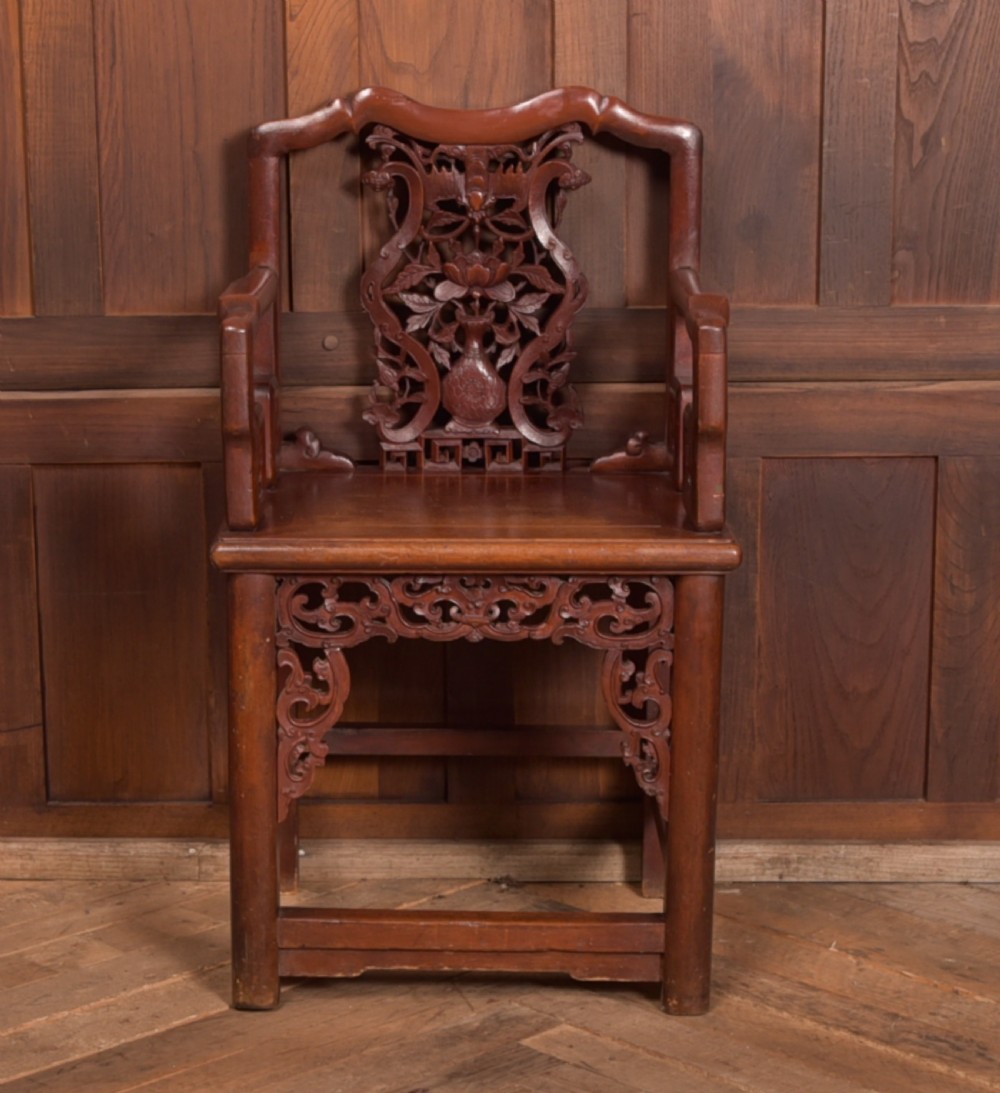 A carved reddish-brown lacquered wooden Chinese armchair featuring an intricate floral splat back, stepped armrests, and decorative carved apron. View VIII