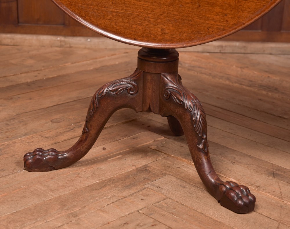 A Georgian mahogany circular snap-top supper table displayed vertically on a turned pedestal stem with carved cabriole legs and ball-and-claw feet. View II