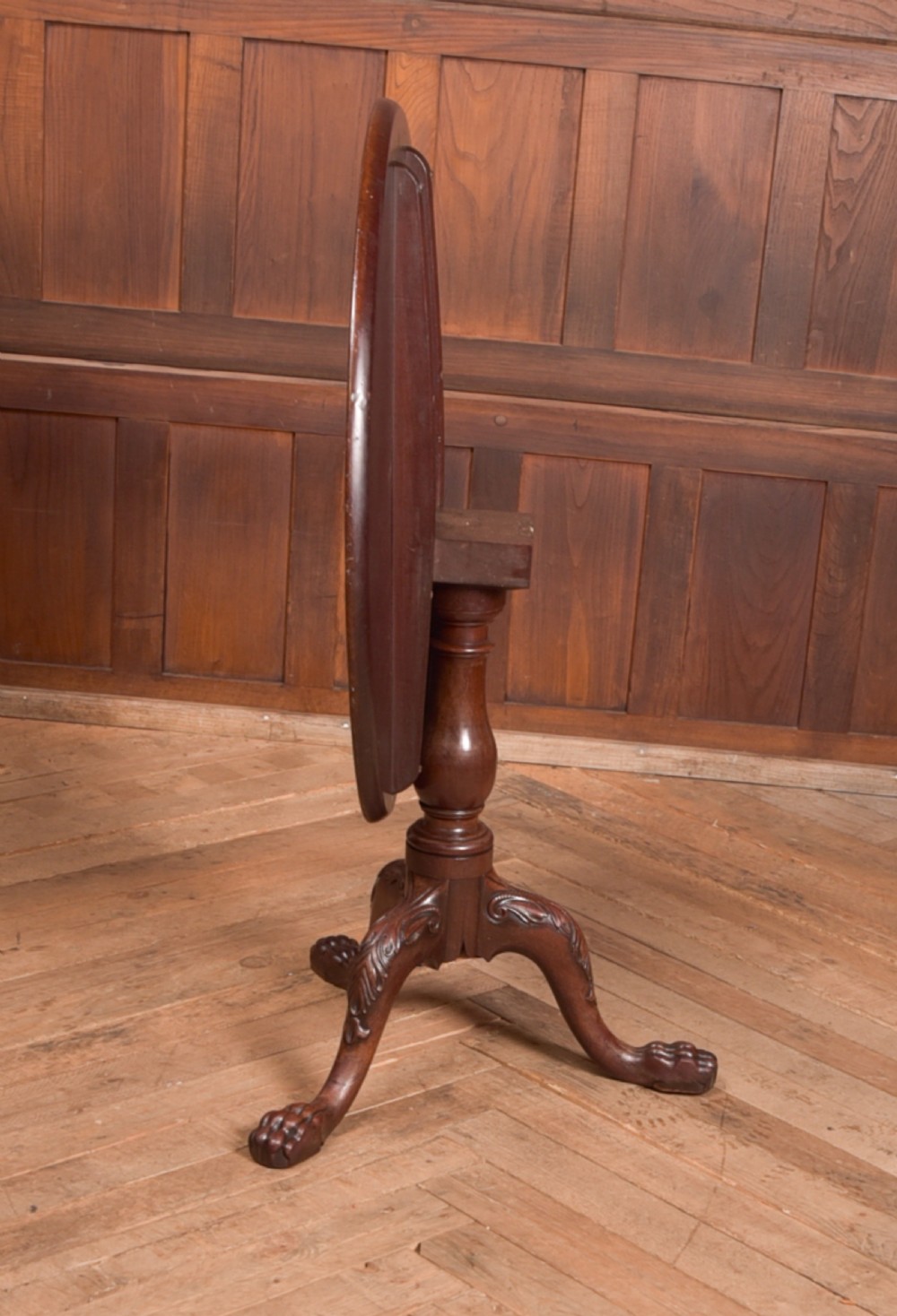 A Georgian mahogany circular snap-top supper table displayed vertically on a turned pedestal stem with carved cabriole legs and ball-and-claw feet. View IV