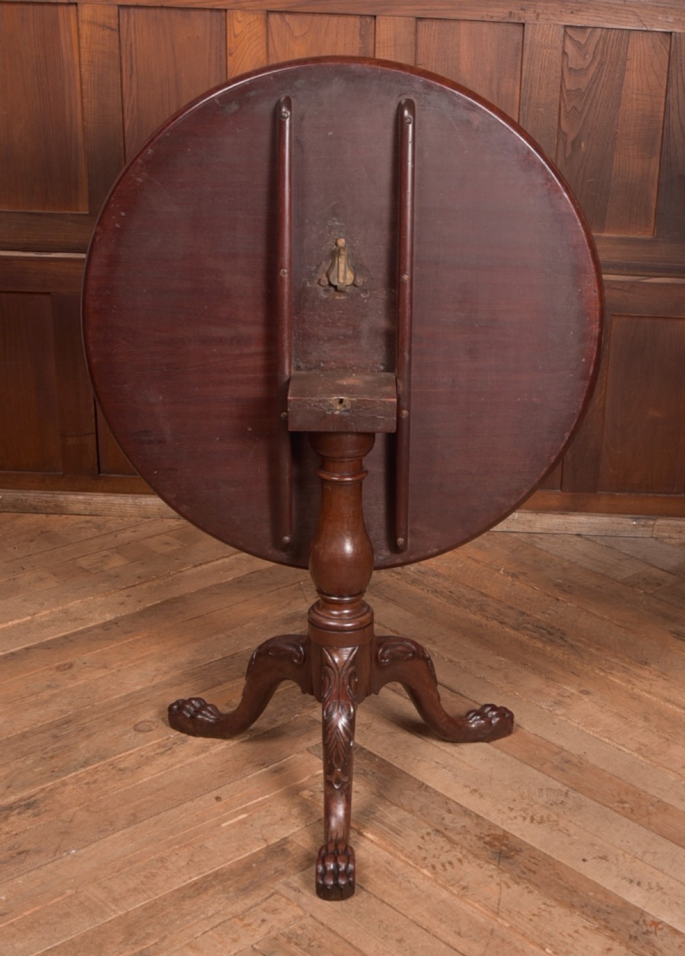 A Georgian mahogany circular snap-top supper table displayed vertically on a turned pedestal stem with carved cabriole legs and ball-and-claw feet. View V