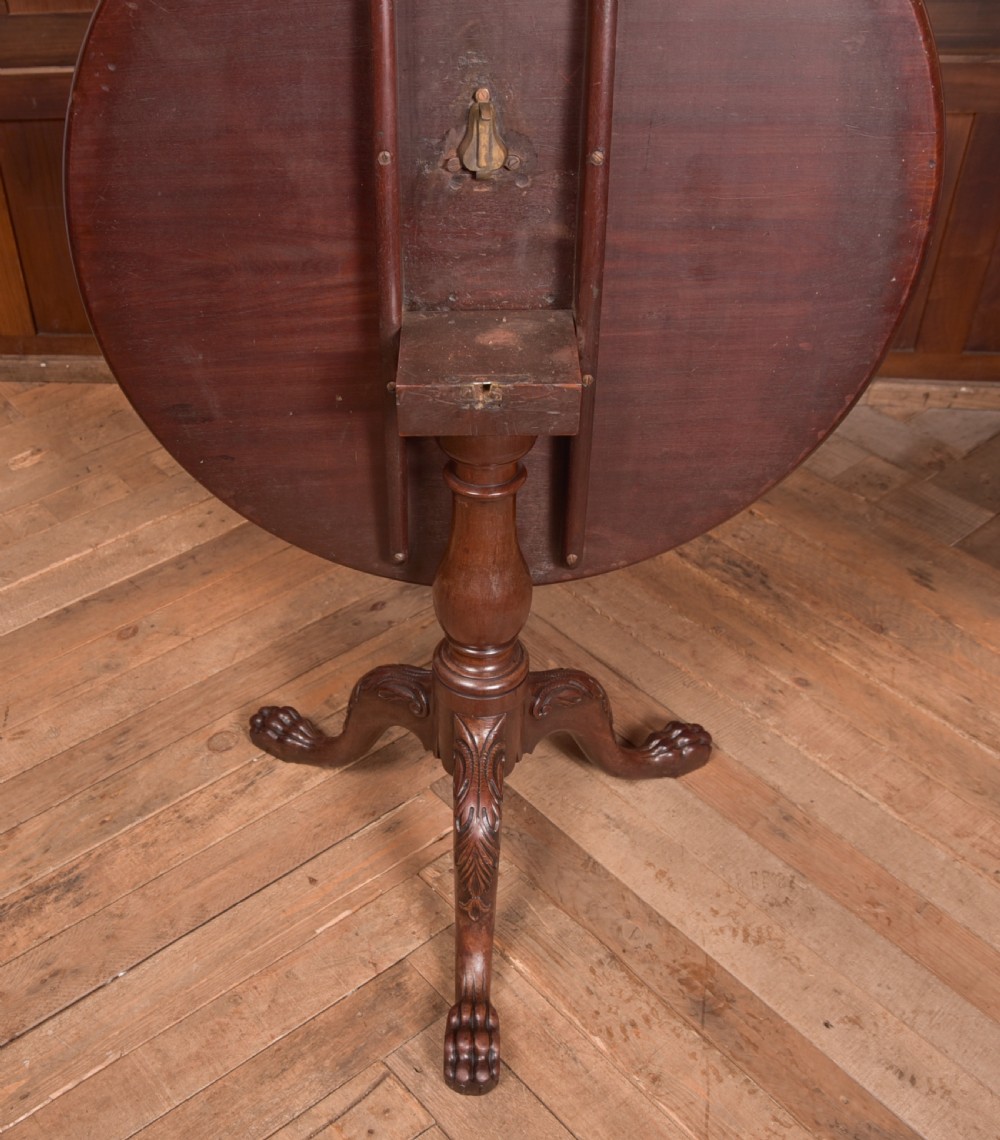 A Georgian mahogany circular snap-top supper table displayed vertically on a turned pedestal stem with carved cabriole legs and ball-and-claw feet. View VI