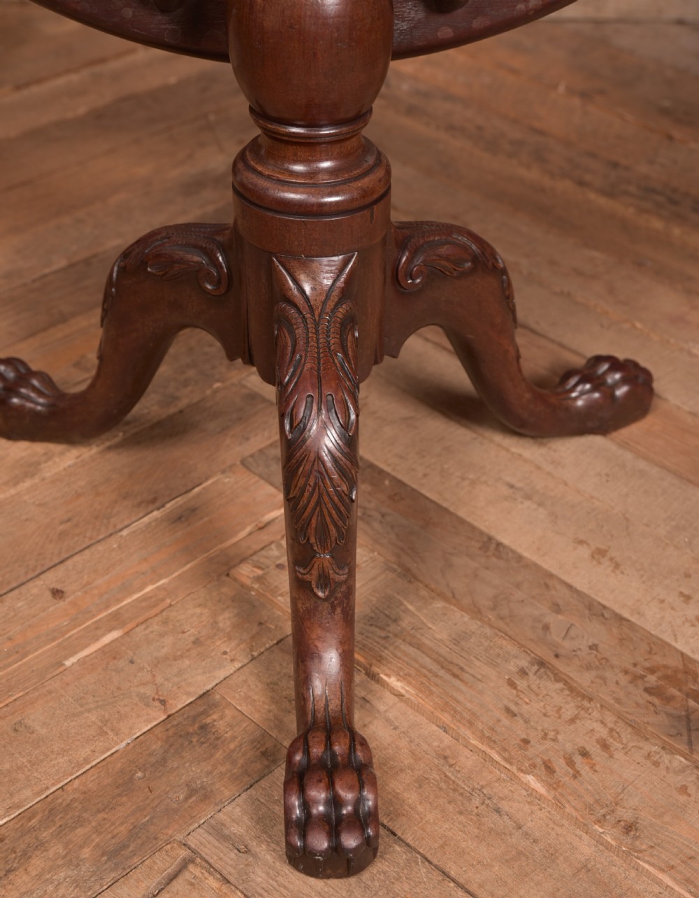 A Georgian mahogany circular snap-top supper table displayed vertically on a turned pedestal stem with carved cabriole legs and ball-and-claw feet. View VII