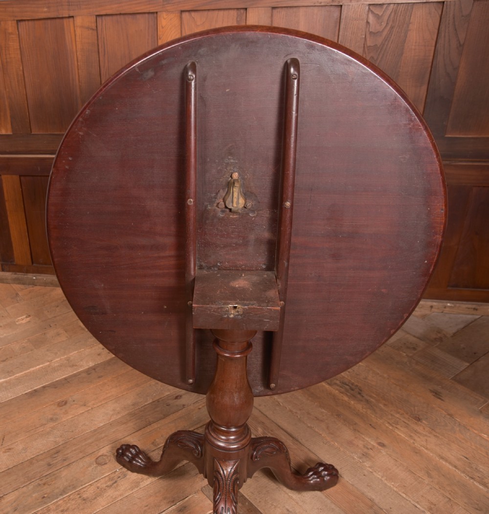 A Georgian mahogany circular snap-top supper table displayed vertically on a turned pedestal stem with carved cabriole legs and ball-and-claw feet. View VIII