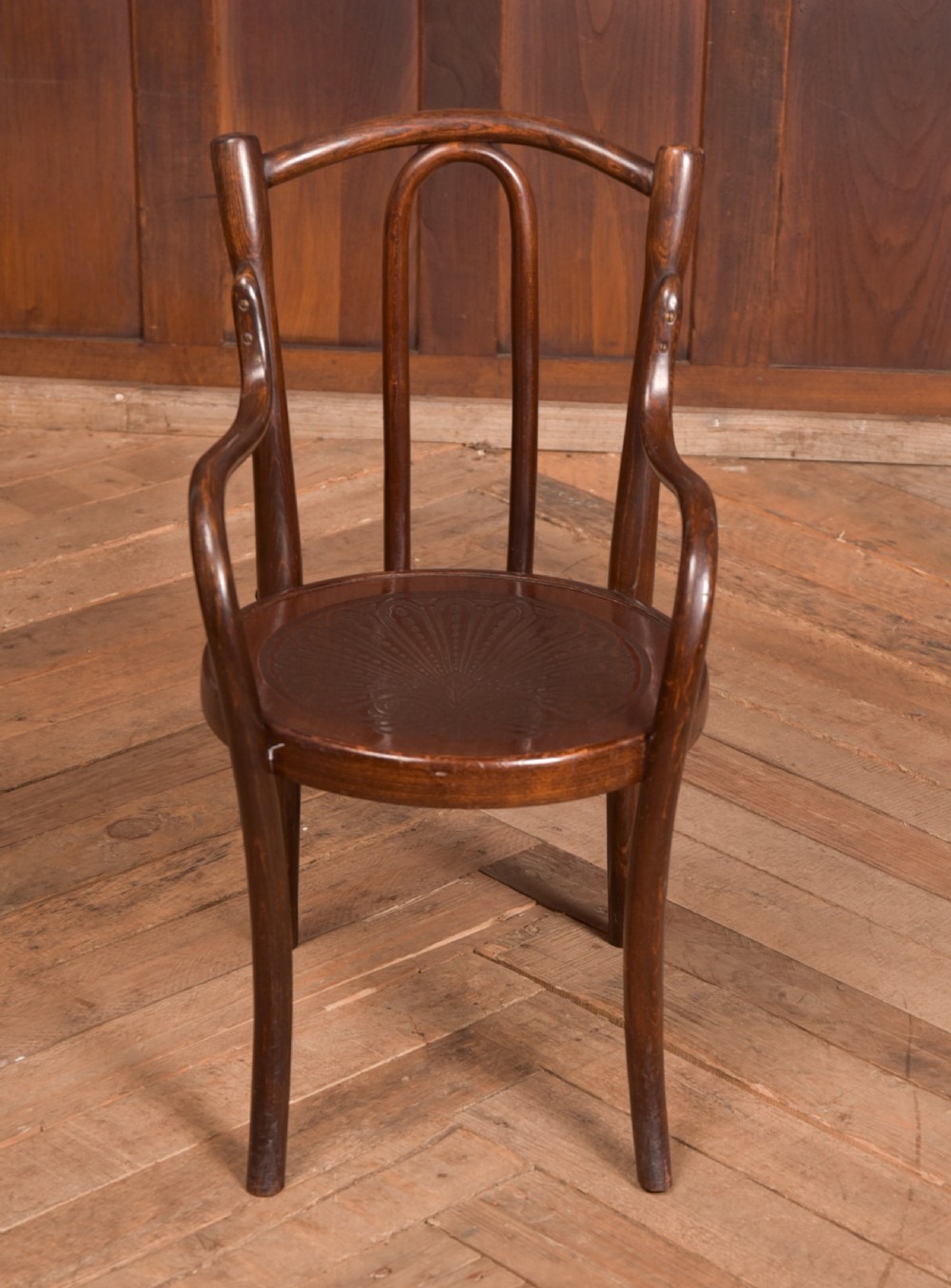 A dark brown childs bentwood armchair featuring a curved backrest, sweeping armrests, and an embossed wooden seat. View VI