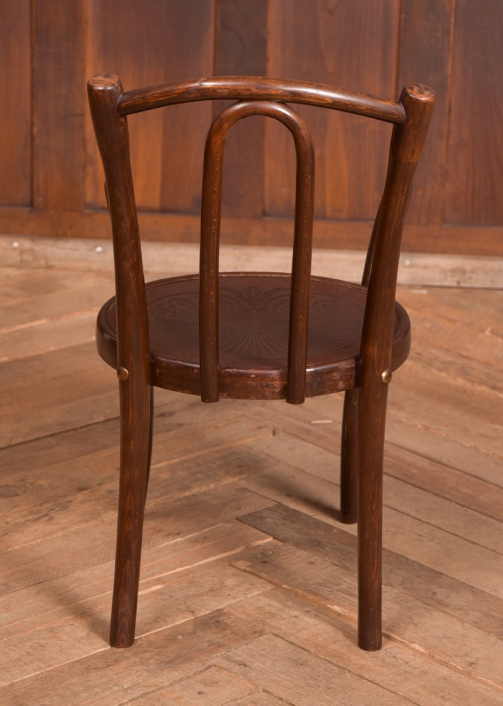 A dark brown childs bentwood armchair featuring a curved backrest, sweeping armrests, and an embossed wooden seat. View VII