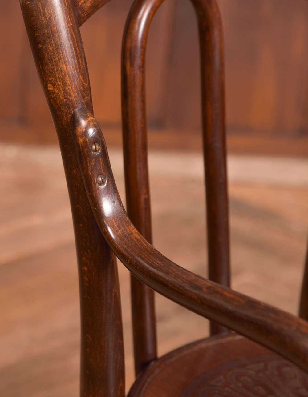 A dark brown childs bentwood armchair featuring a curved backrest, sweeping armrests, and an embossed wooden seat. View VIII
