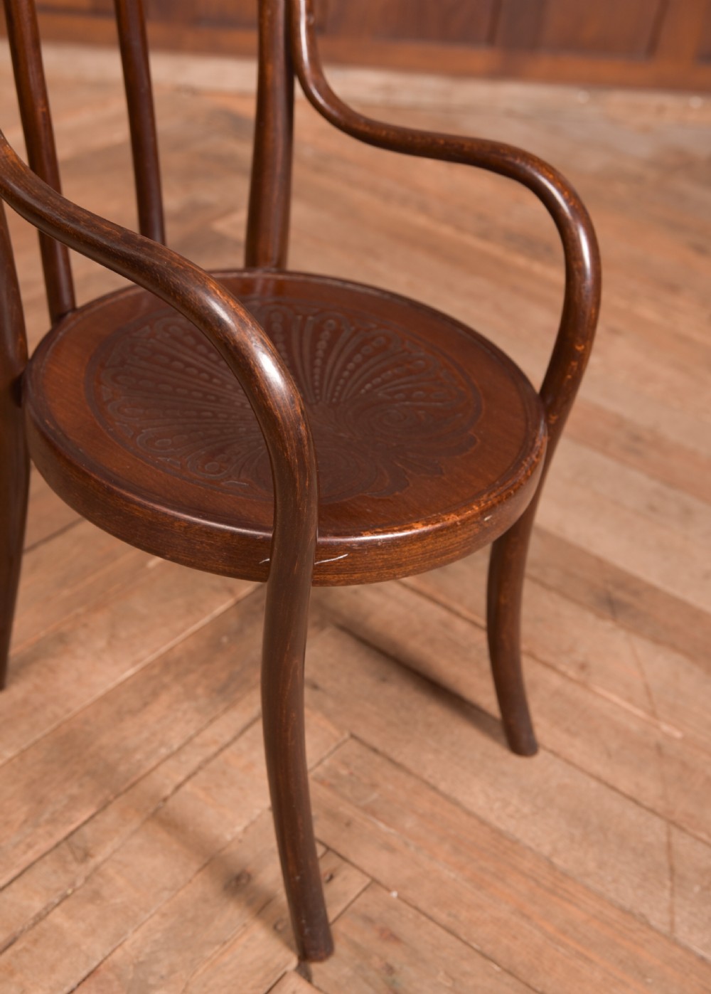 A dark brown childs bentwood armchair featuring a curved backrest, sweeping armrests, and an embossed wooden seat. View XI