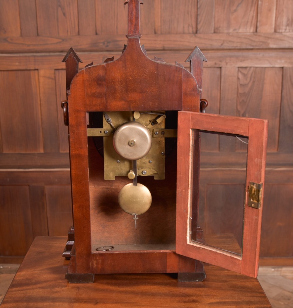 An antique mahogany bracket clock featuring Gothic spire finials, a carved foliage crest, and a cream dial signed Christie Perth set within a brass bezel. View XII