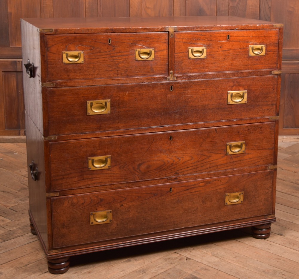 A nineteenth-century teak military campaign chest of drawers with flush brass handles, corner brackets, and turned feet.