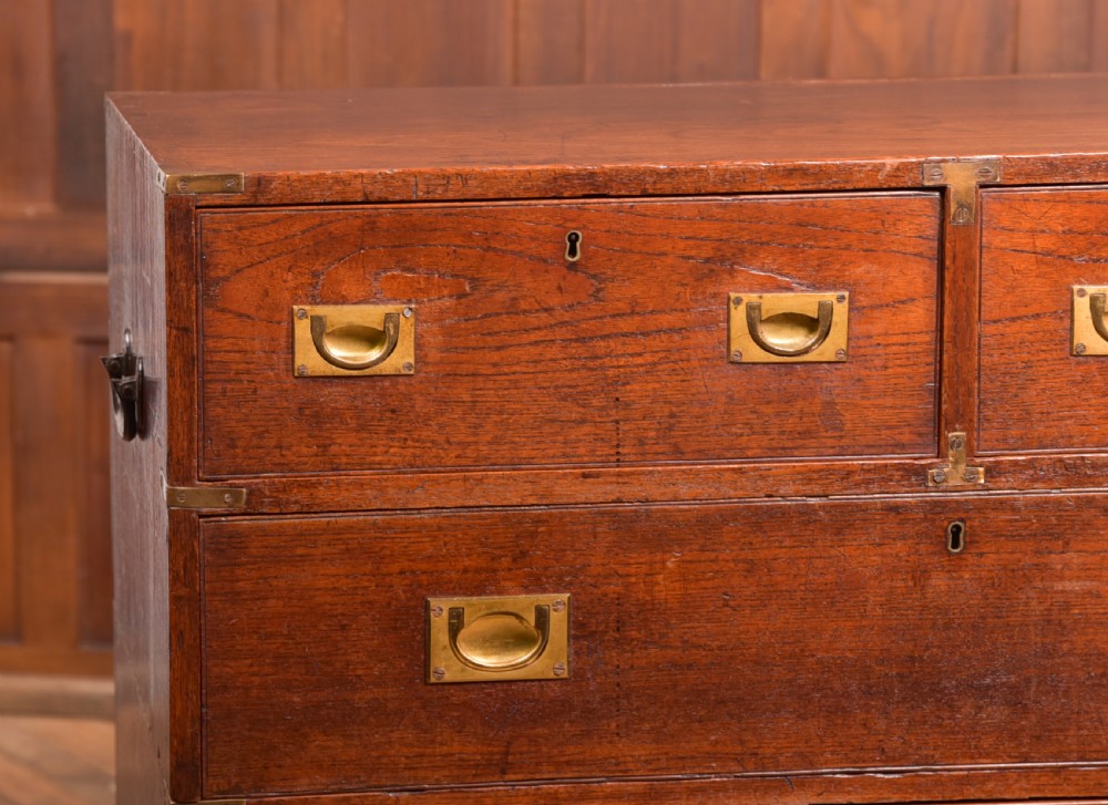 A nineteenth-century teak military campaign chest of drawers with flush brass handles, corner brackets, and turned feet. View II