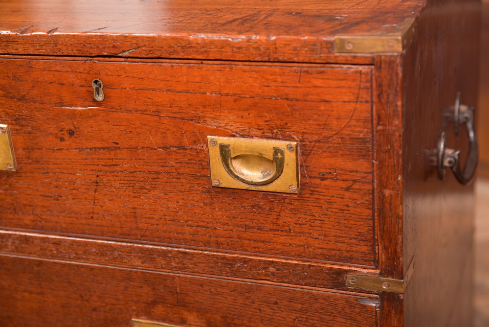 A nineteenth-century teak military campaign chest of drawers with flush brass handles, corner brackets, and turned feet. View III