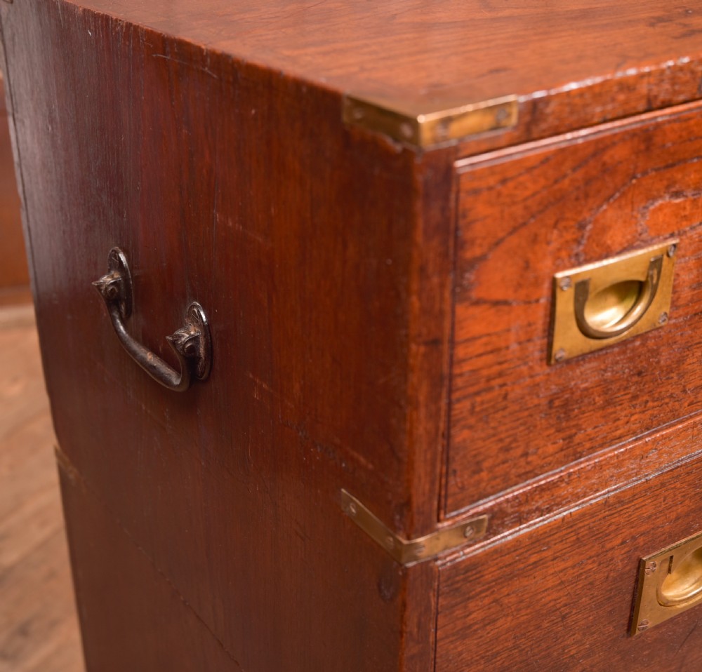 A nineteenth-century teak military campaign chest of drawers with flush brass handles, corner brackets, and turned feet. View VI