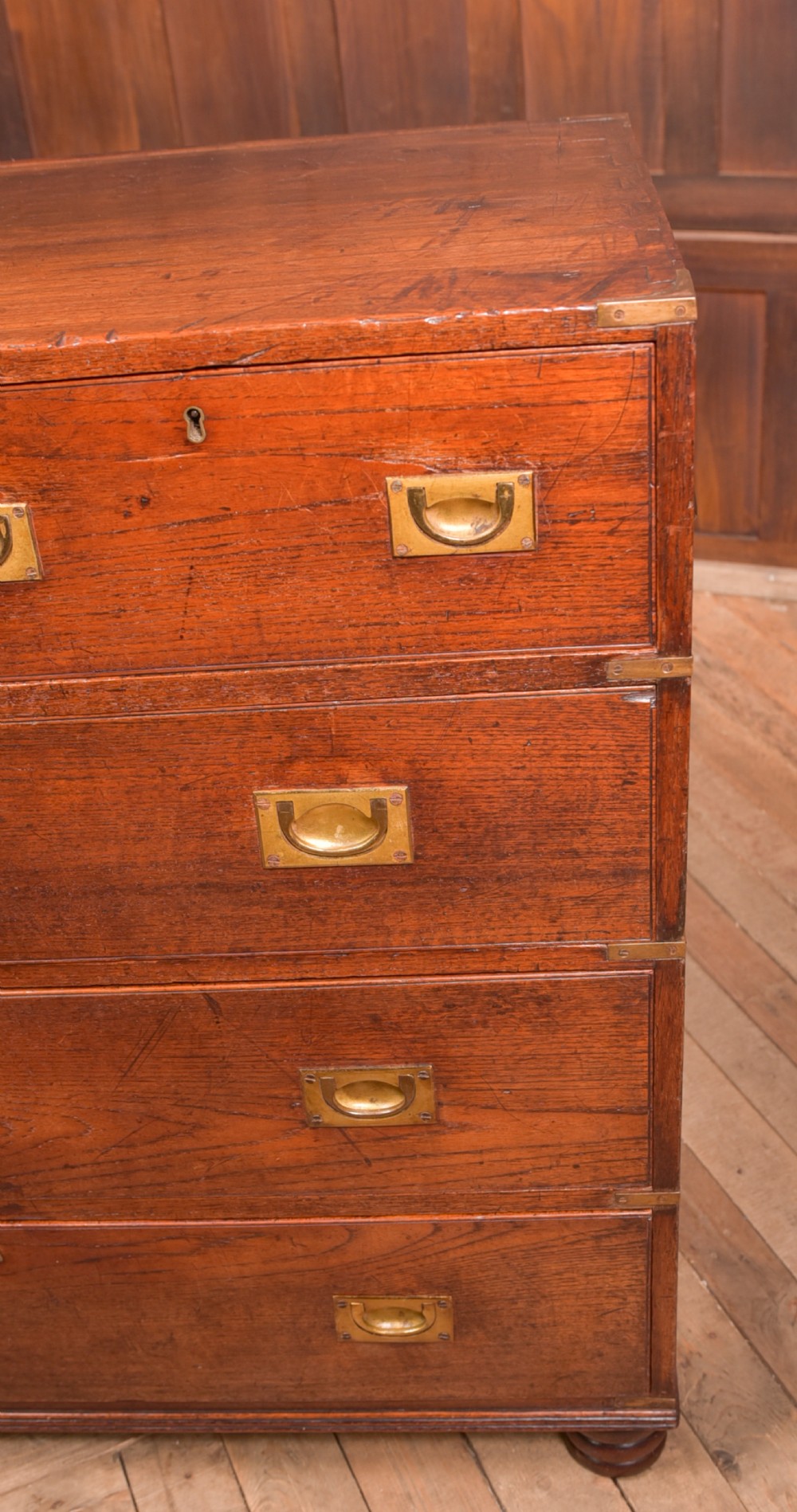 A nineteenth-century teak military campaign chest of drawers with flush brass handles, corner brackets, and turned feet. View IX