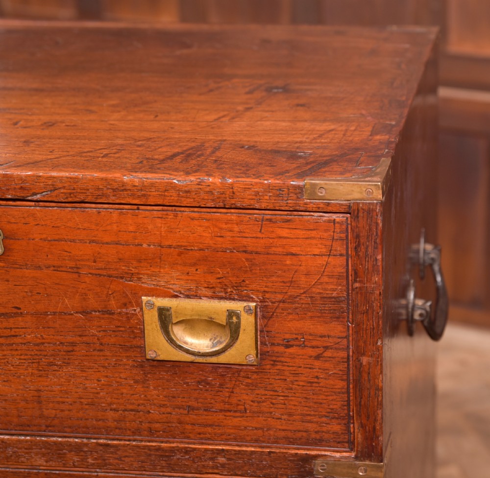 A nineteenth-century teak military campaign chest of drawers with flush brass handles, corner brackets, and turned feet. View X