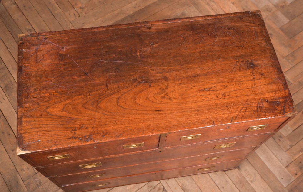 A nineteenth-century teak military campaign chest of drawers with flush brass handles, corner brackets, and turned feet. View XII