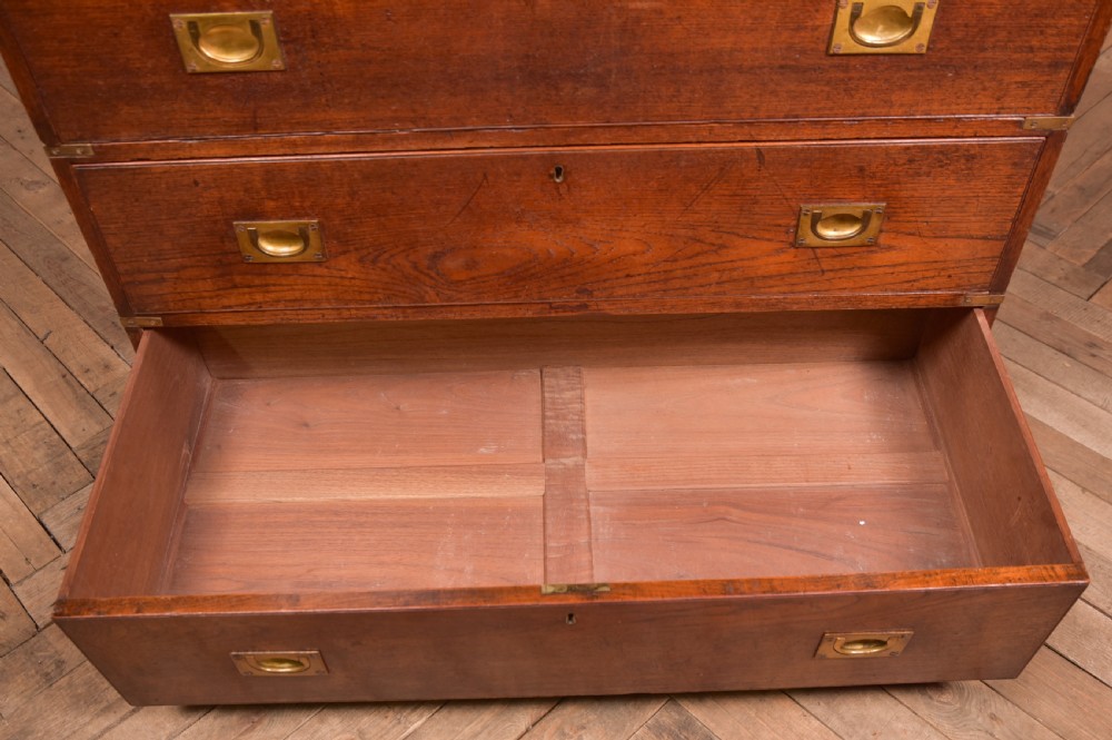 A nineteenth-century teak military campaign chest of drawers with flush brass handles, corner brackets, and turned feet. View XIII