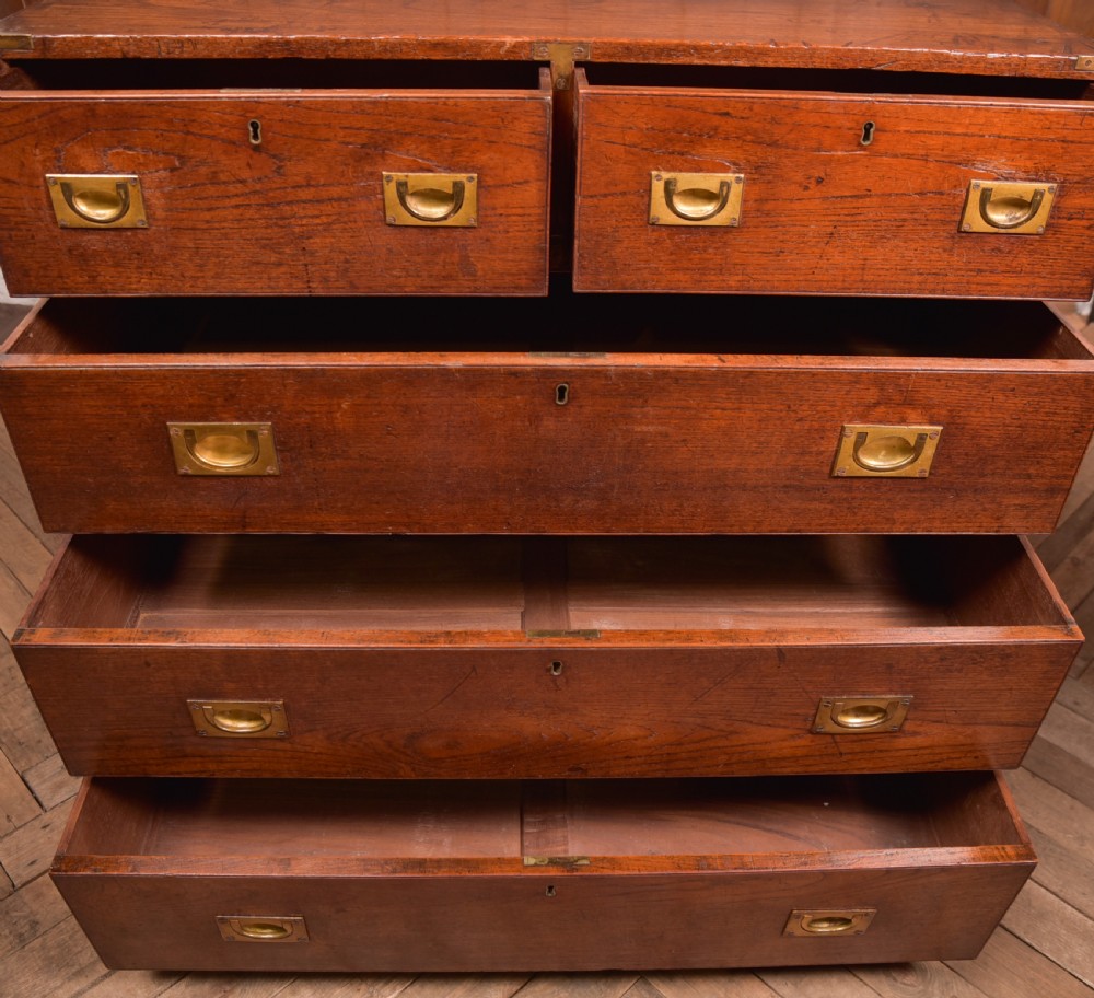 A nineteenth-century teak military campaign chest of drawers with flush brass handles, corner brackets, and turned feet. View XV