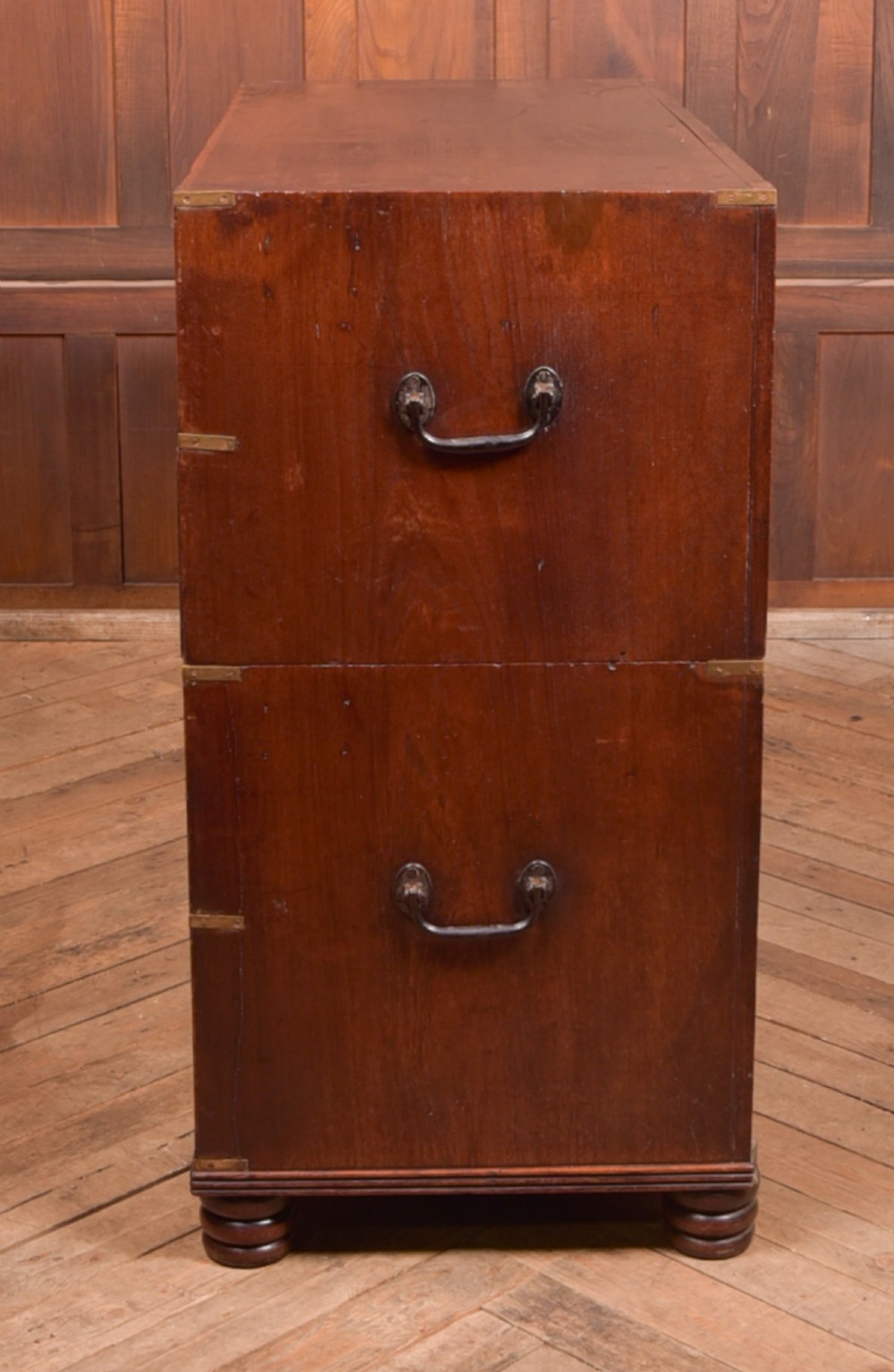 A nineteenth-century teak military campaign chest of drawers with flush brass handles, corner brackets, and turned feet. View XVII