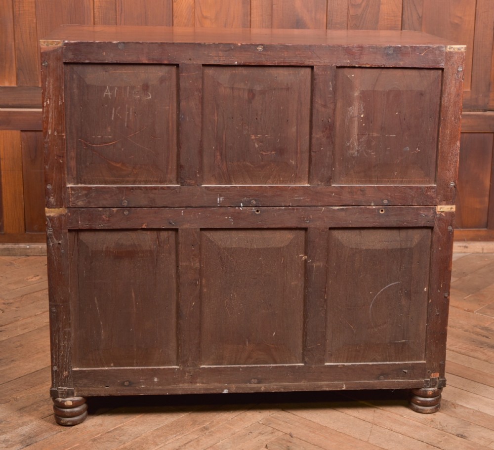 A nineteenth-century teak military campaign chest of drawers with flush brass handles, corner brackets, and turned feet. View XX