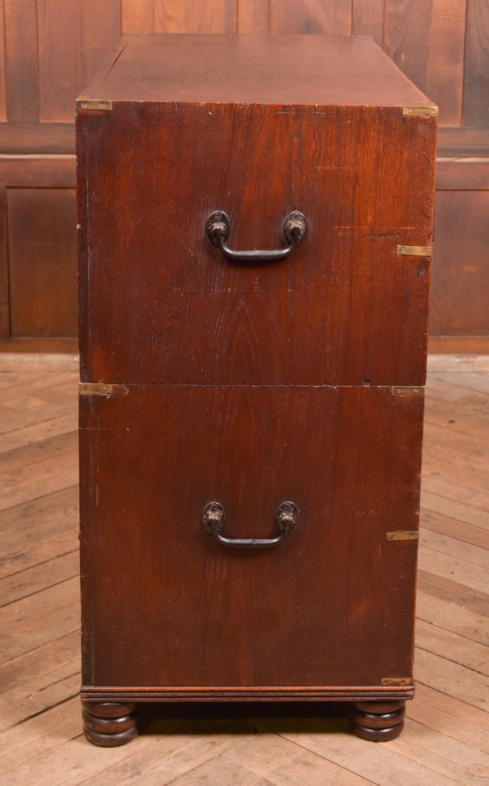 A nineteenth-century teak military campaign chest of drawers with flush brass handles, corner brackets, and turned feet. View XXI