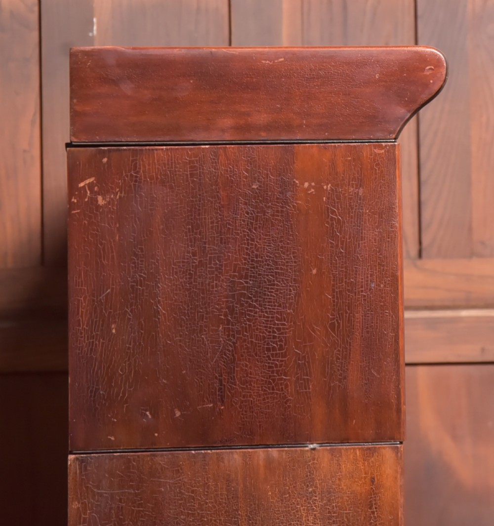 A large double-width mahogany sectional bookcase featuring three tiers of glazed lift-up doors filled with antique books above a solid wooden double cupboard base. View XVII