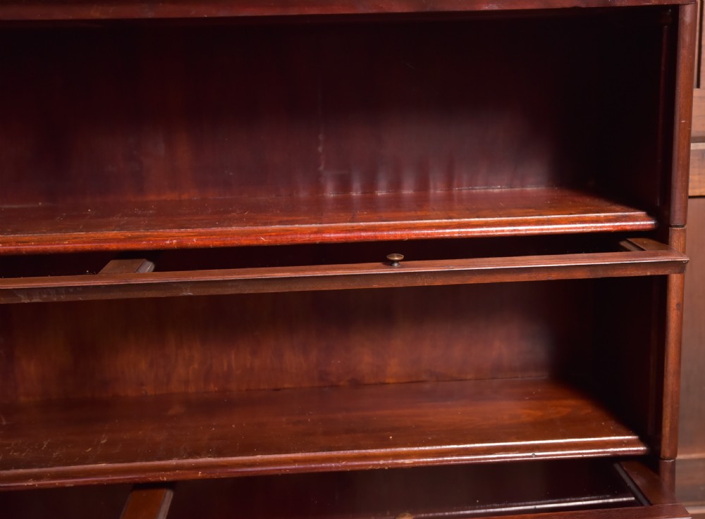 A large double-width mahogany sectional bookcase featuring three tiers of glazed lift-up doors filled with antique books above a solid wooden double cupboard base. View XVIII