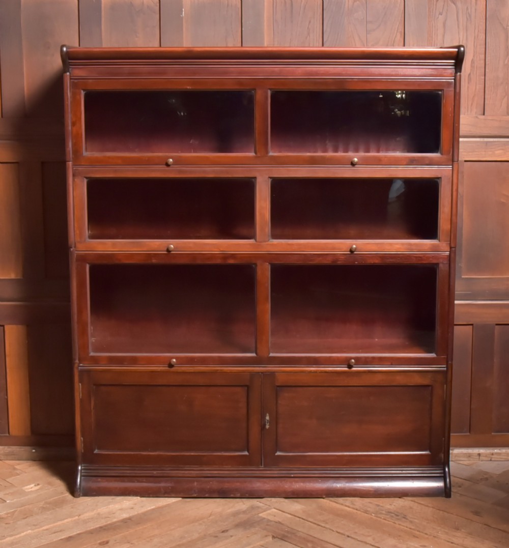 A large double-width mahogany sectional bookcase featuring three tiers of glazed lift-up doors filled with antique books above a solid wooden double cupboard base. View XX