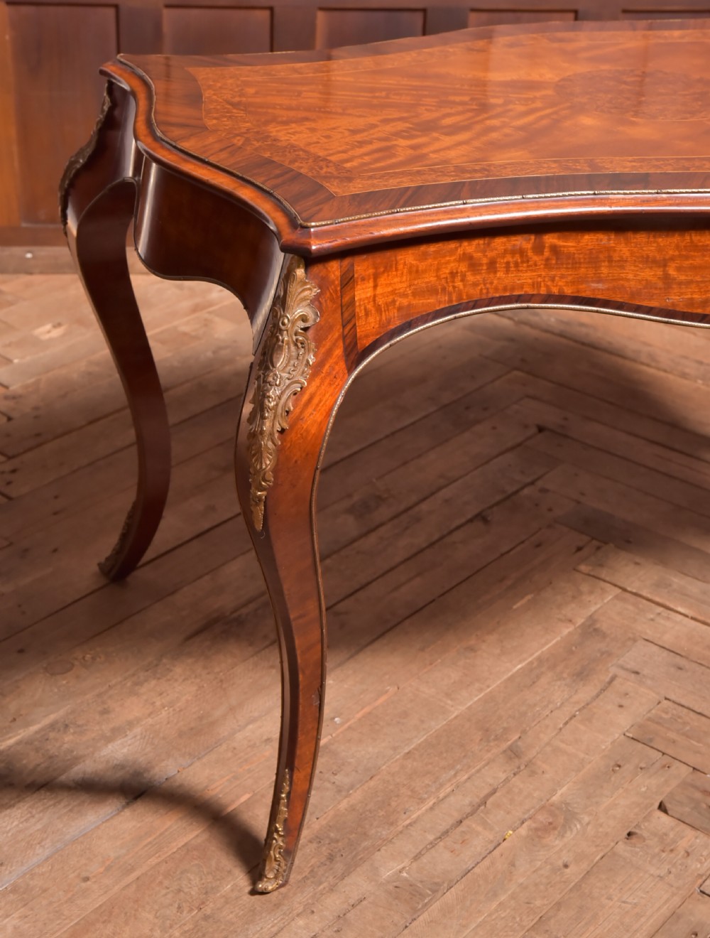 A Victorian walnut centre table featuring a serpentine top, gilt ormolu mounts, and cabriole legs on a parquet floor. View II
