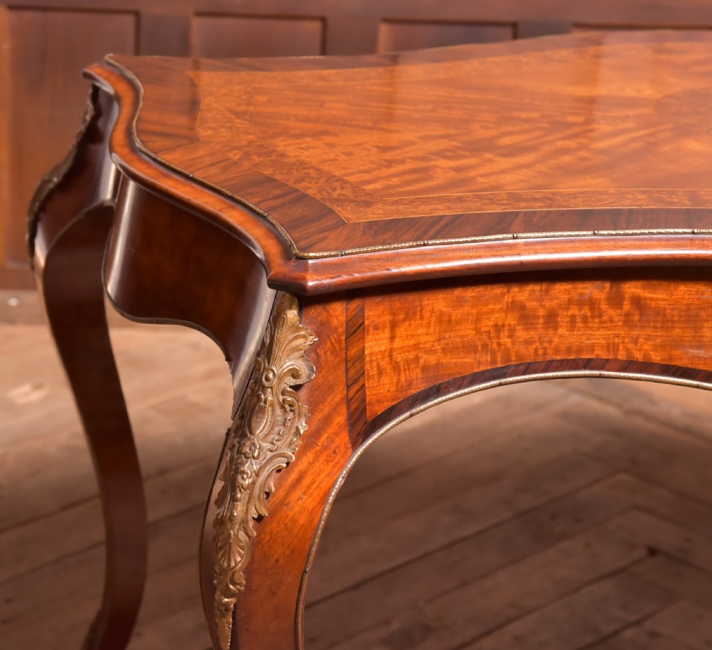 A Victorian walnut centre table featuring a serpentine top, gilt ormolu mounts, and cabriole legs on a parquet floor. View III