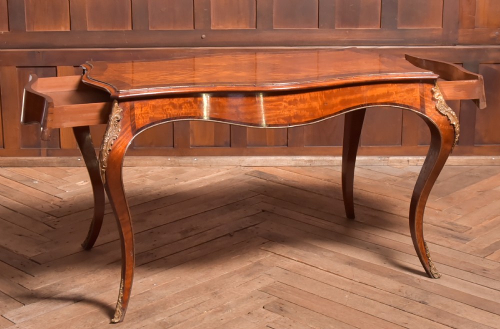 A Victorian walnut centre table featuring a serpentine top, gilt ormolu mounts, and cabriole legs on a parquet floor. View VII