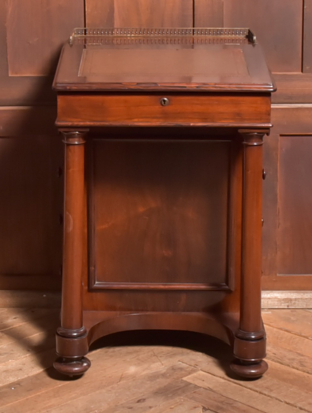 A Victorian rosewood Davenport desk featuring a slanted leather-inset writing surface, brass gallery rail, turned front columns, and side drawers. View II