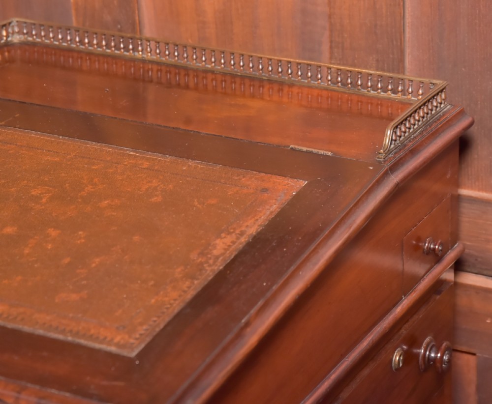 A Victorian rosewood Davenport desk featuring a slanted leather-inset writing surface, brass gallery rail, turned front columns, and side drawers. View III