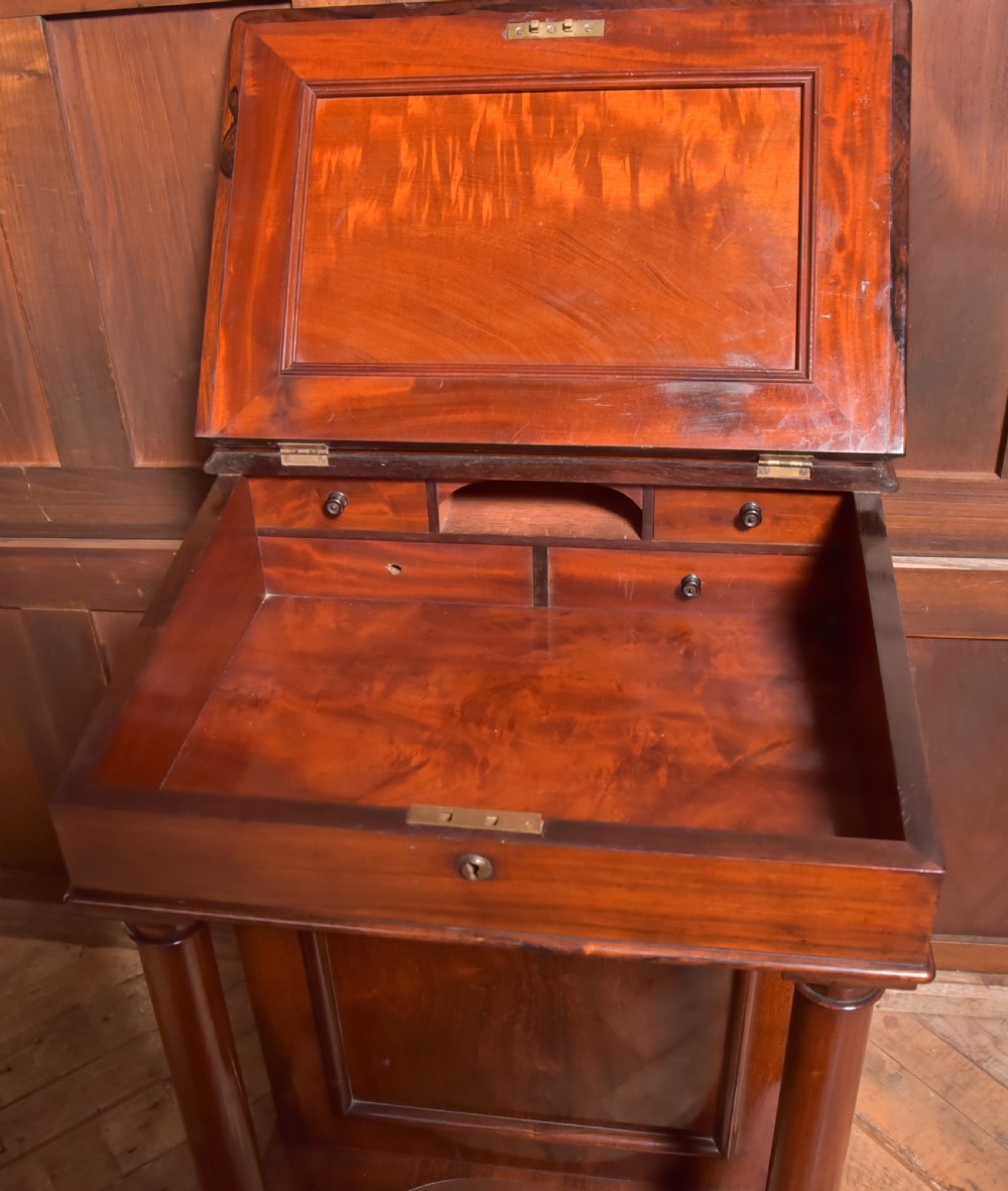 A Victorian rosewood Davenport desk featuring a slanted leather-inset writing surface, brass gallery rail, turned front columns, and side drawers. View VI