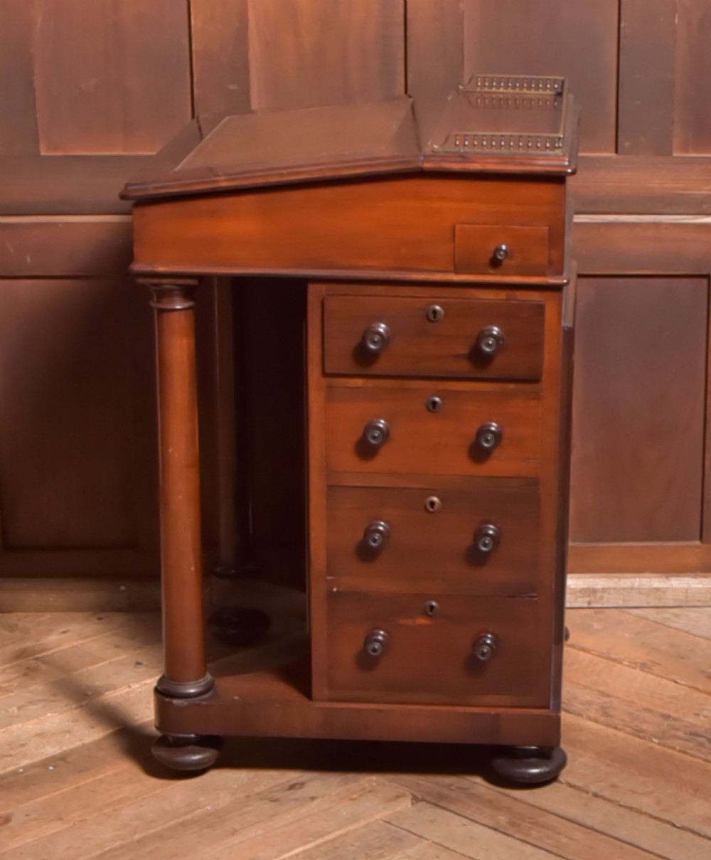 A Victorian rosewood Davenport desk featuring a slanted leather-inset writing surface, brass gallery rail, turned front columns, and side drawers. View VII