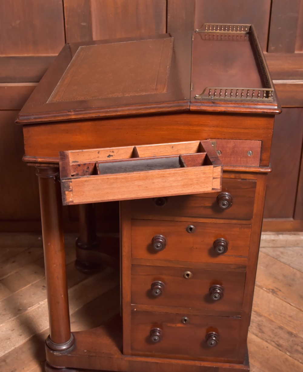 A Victorian rosewood Davenport desk featuring a slanted leather-inset writing surface, brass gallery rail, turned front columns, and side drawers. View VIII