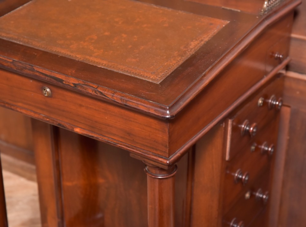 A Victorian rosewood Davenport desk featuring a slanted leather-inset writing surface, brass gallery rail, turned front columns, and side drawers. View IX