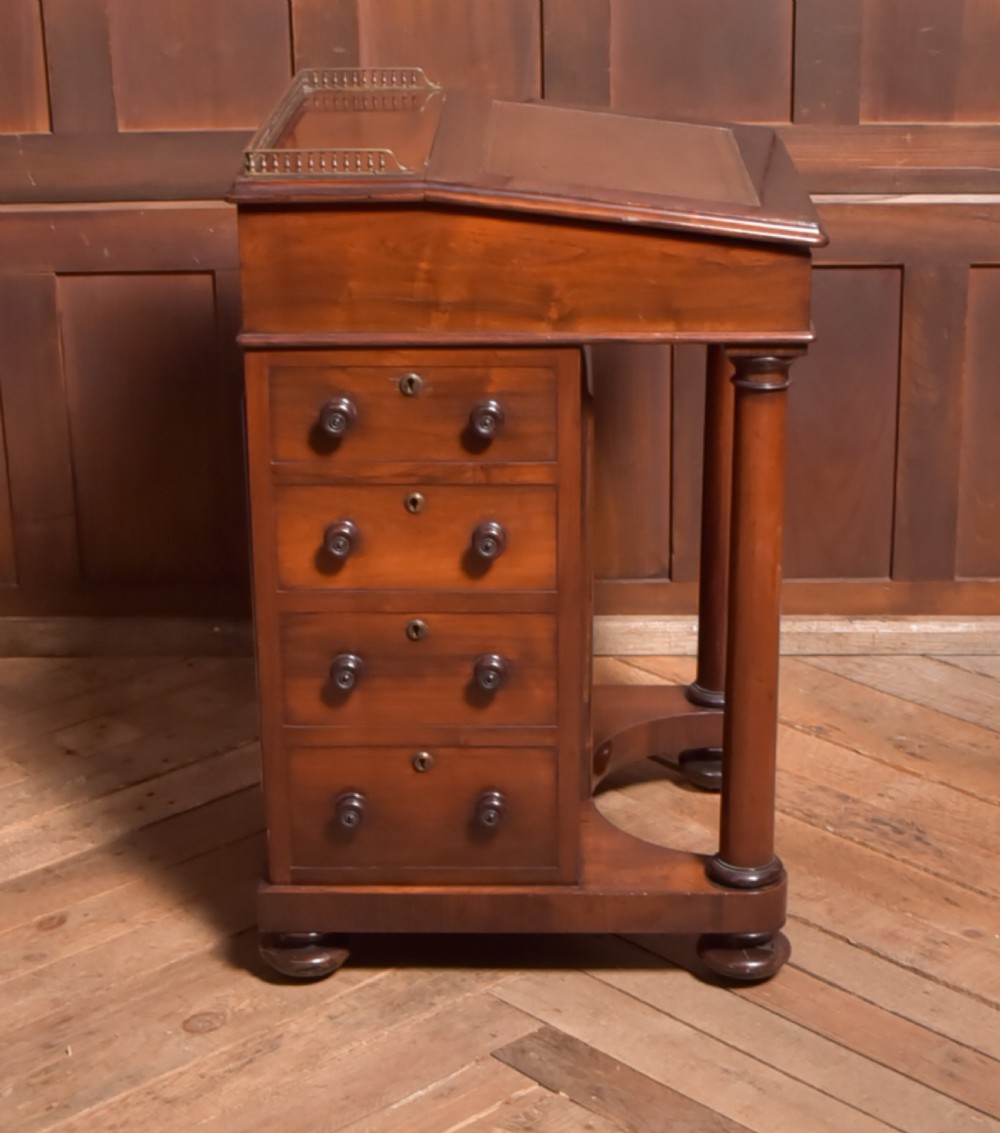 A Victorian rosewood Davenport desk featuring a slanted leather-inset writing surface, brass gallery rail, turned front columns, and side drawers. View XIII